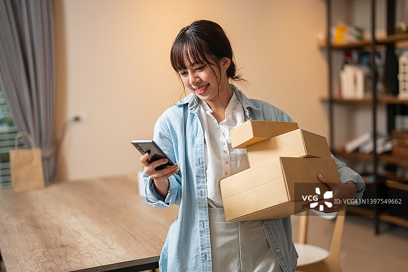 用智能手机接收包裹的快乐年轻女性图片素材