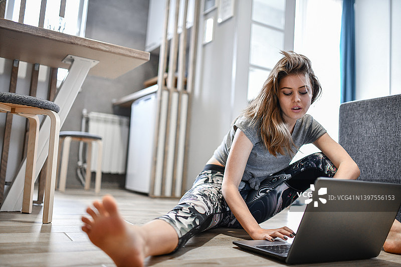 女运动员在家用笔记本电脑选择锻炼项目图片素材