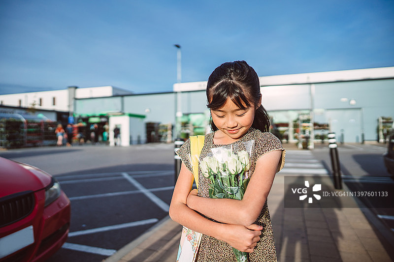 在超市外抱着一束白玫瑰的快乐女孩图片素材