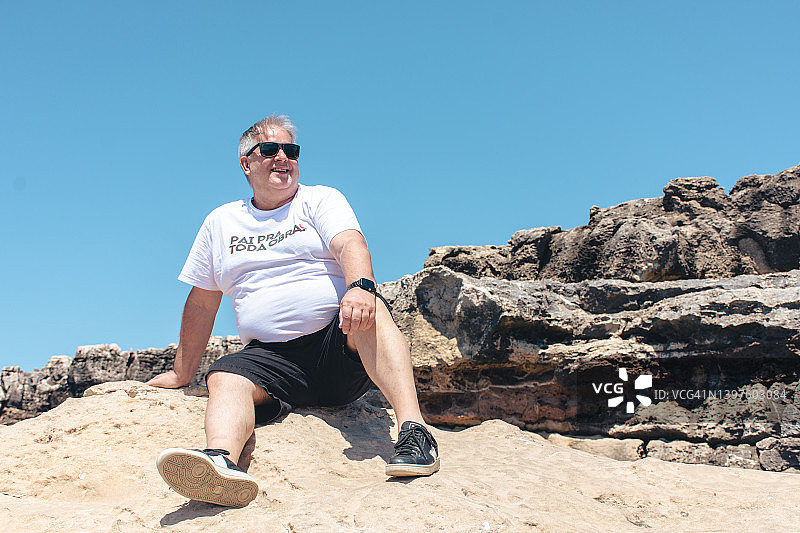 坐在地狱之口岩石上的男人图片素材