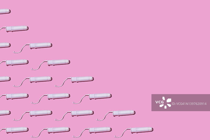 粉色背景下的纤维素卫生棉条纹理，左侧带有细绳，月经、排卵、生殖、疼痛和个人卫生概念图片素材