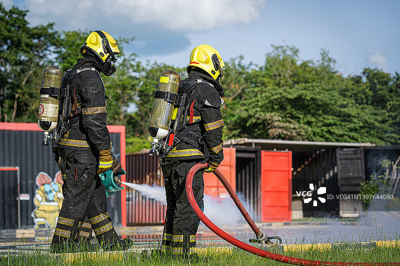 消防员在训练中灭火，使用灭火器和消防水带喷水灭火图片素材