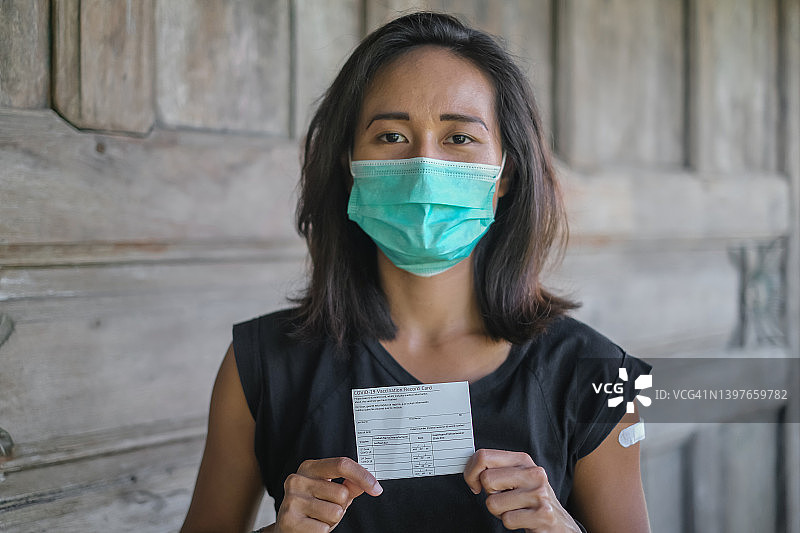 自豪的印度尼西亚妇女展示她的Covid-19疫苗接种记录卡证书图片素材