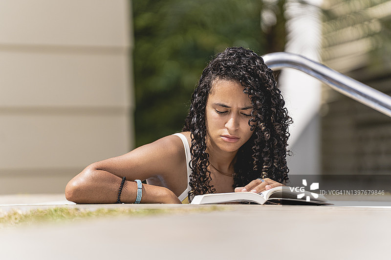 严肃的美丽女人在游泳池阅读图片素材