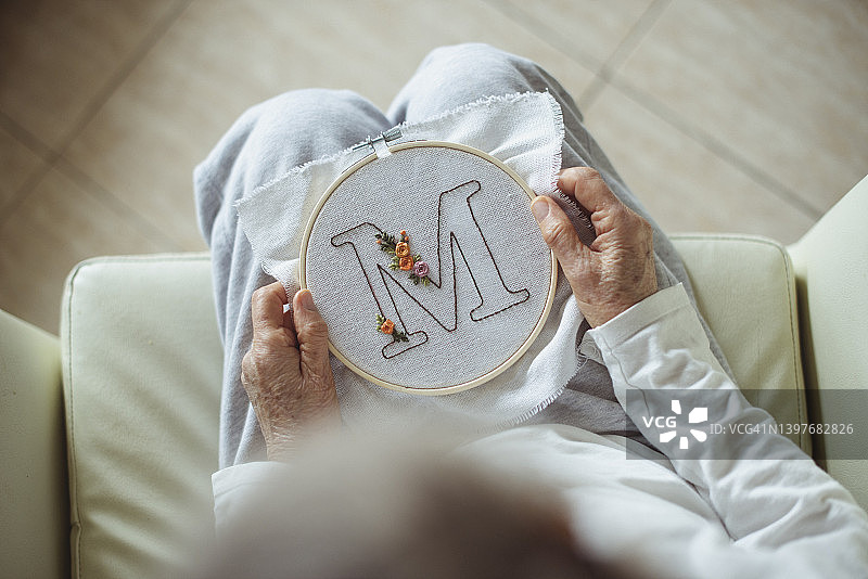 女人手持字母M刺绣绷架俯视图片素材