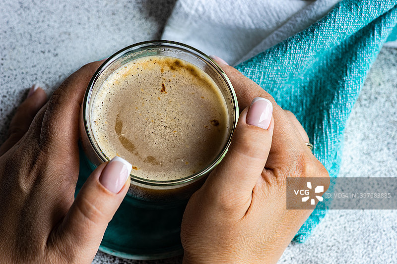 女人手捧咖啡杯的桌面俯视图图片素材