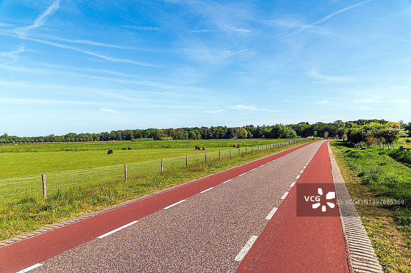 阳光明媚的日子里，带有自行车道的乡间道路图片素材