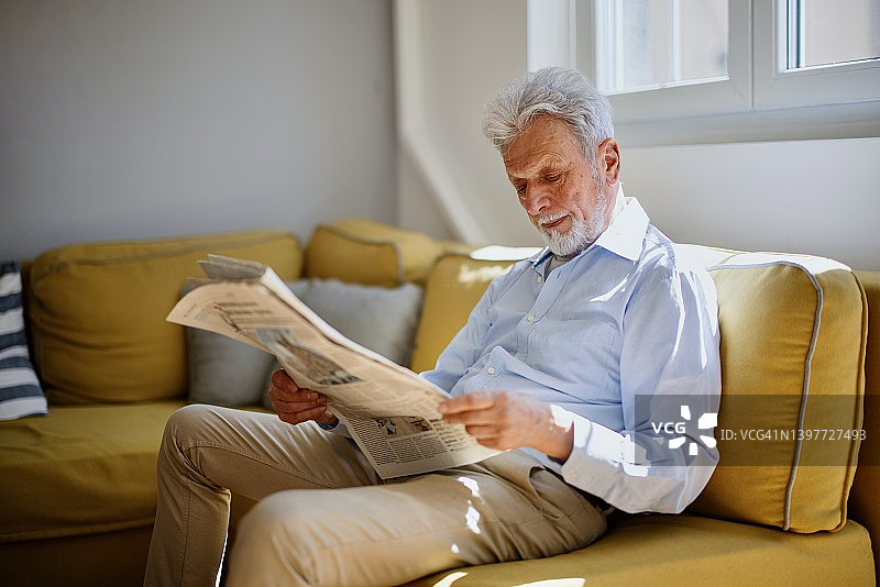 老年男人在居家放松的一天里读报纸图片素材