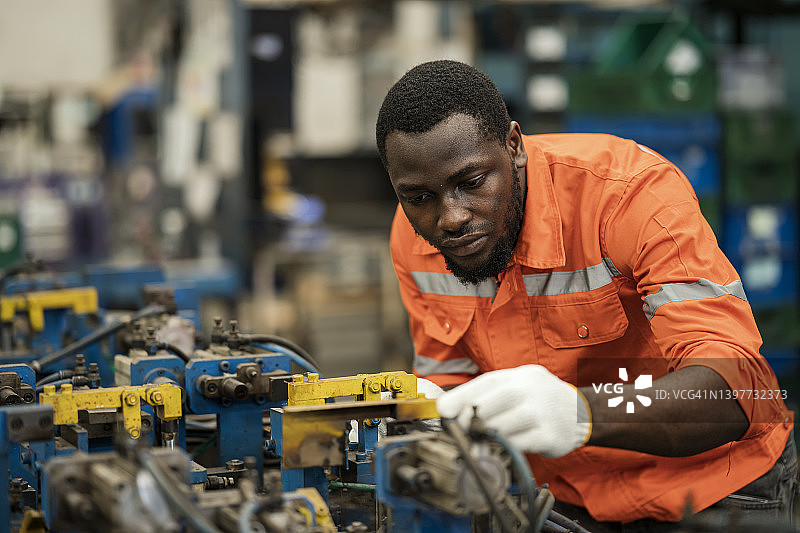 提高制造行业零件质量的装配夹具：非裔美国技术人员使用工具调整和维修生产线车间的工程零件装配焊接夹具图片素材
