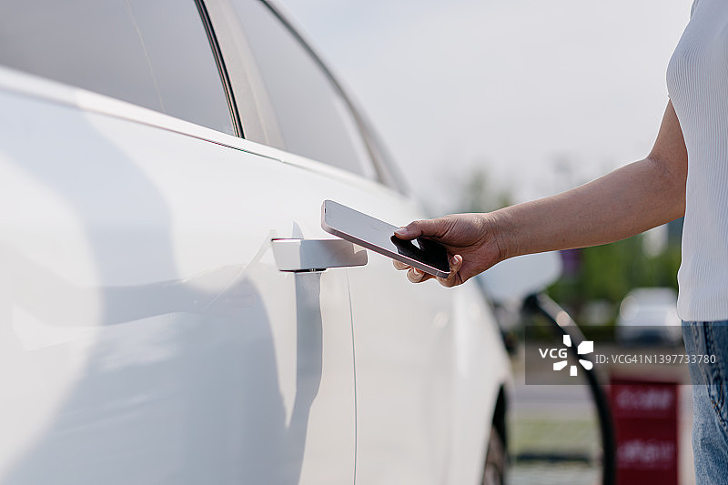 亚洲年轻女子正在用智能手机解锁汽车图片素材