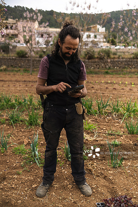 年轻农场主用手机查看订单，面带笑容图片素材