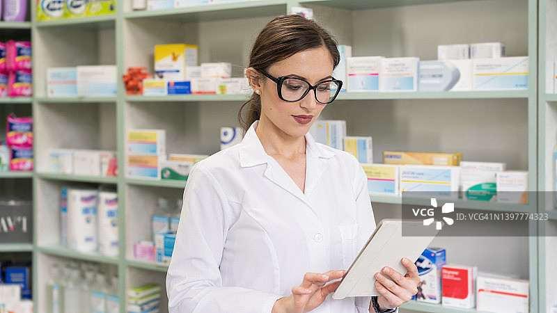 年轻女药剂师拿着药片，管理处方并检查药物图片素材