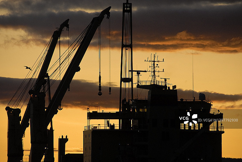 日落时分带有起重机的工业船图片素材