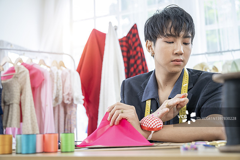 自信的年轻男子在工作台上工作。小型企业时装设计师概念。图片素材