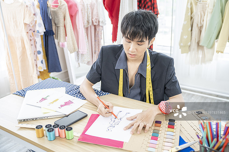 年轻自信的男时装设计师在时装设计工作室的工作台上素描和绘画图片素材