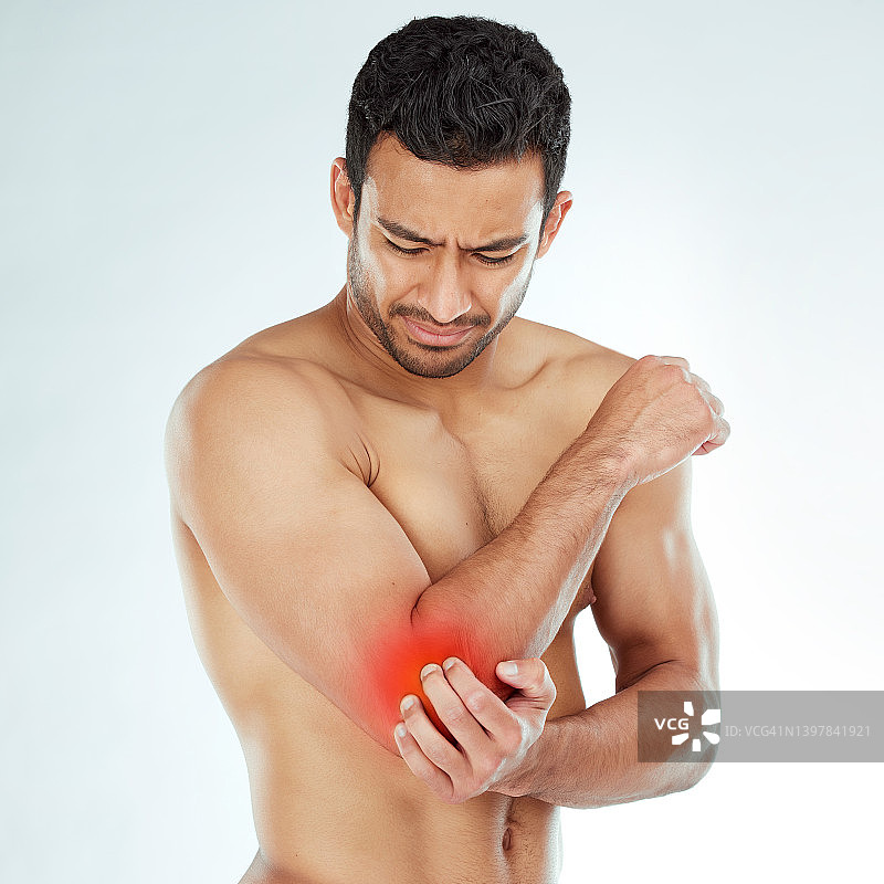 男子在影棚背景下痛苦地扶着胳膊图片素材