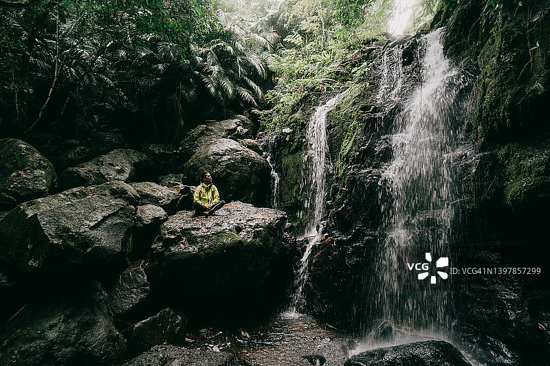坐在雨林瀑布前的男人图片素材