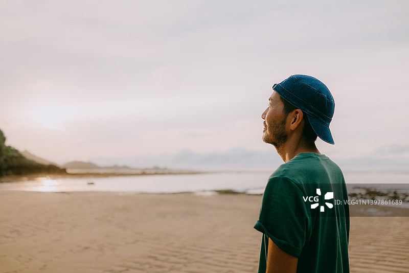 男人在海滩日落时朝远处看图片素材