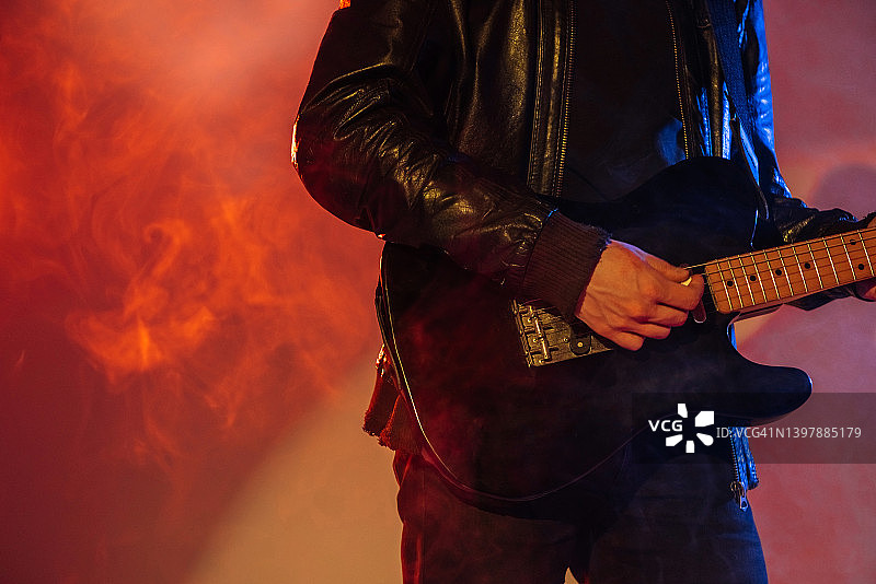吉他特写。吉他手在彩色烟雾背景下演奏乐器。音乐节广告，带文案空间图片素材