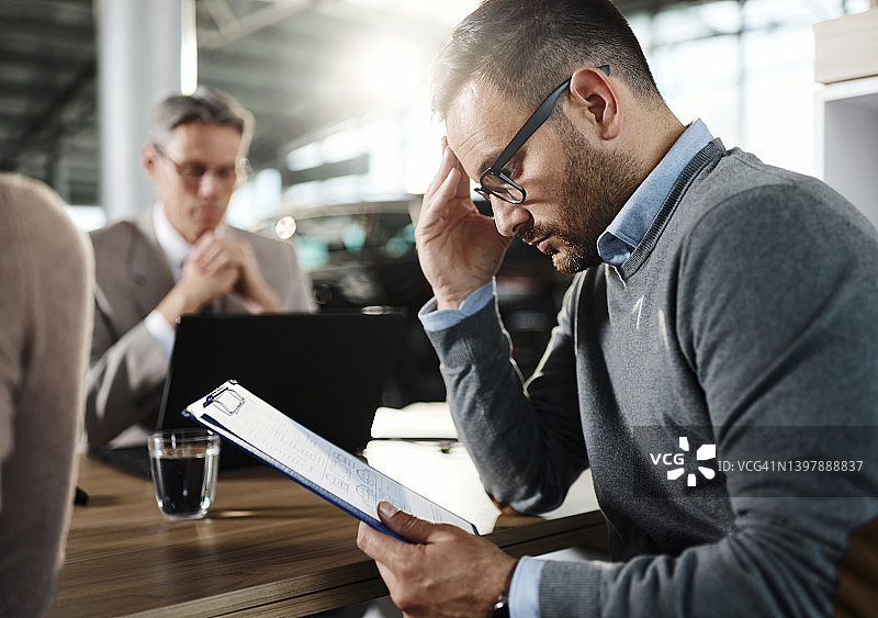 在汽车展厅的会议上审查合同的年轻男人图片素材