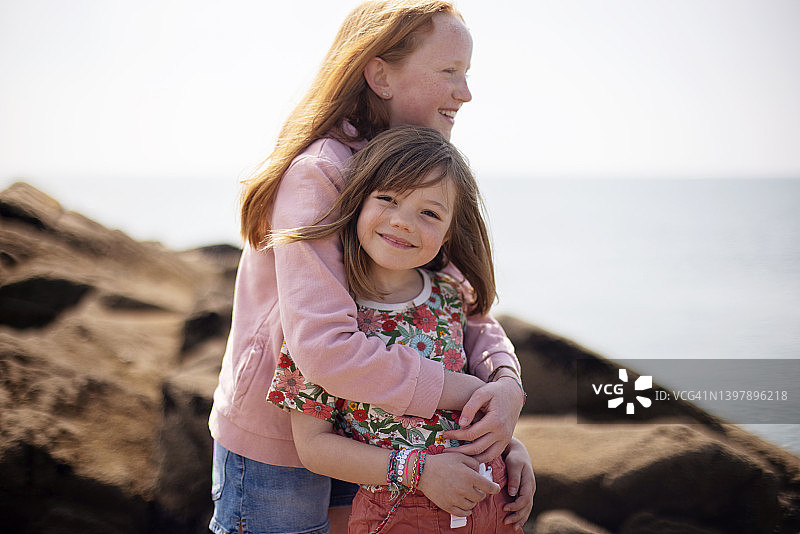 站在岩石上的两个微笑女孩图片素材