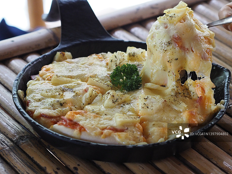 女士手拿夏威夷披萨：火腿、培根、菠萝和披萨酱图片素材