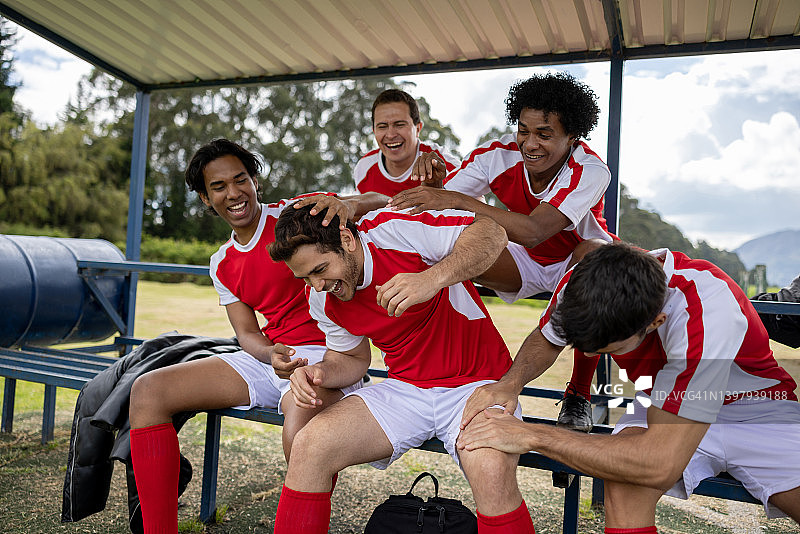一群足球运动员在替补席上戏弄队友并大笑图片素材
