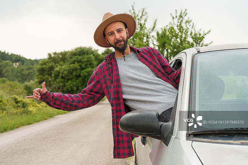 快乐的男人探出车窗，用手势打招呼图片素材