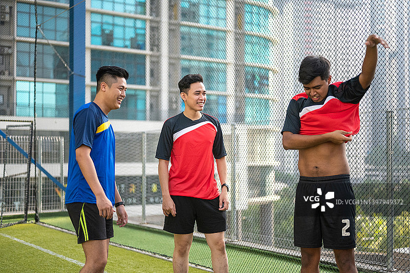 快乐的年轻亚洲男子足球队准备参加早晨训练，整理运动服图片素材