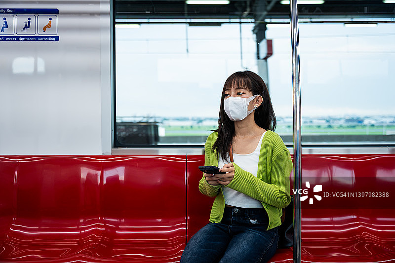 年轻的亚洲女性在上下班途中使用智能手机图片素材