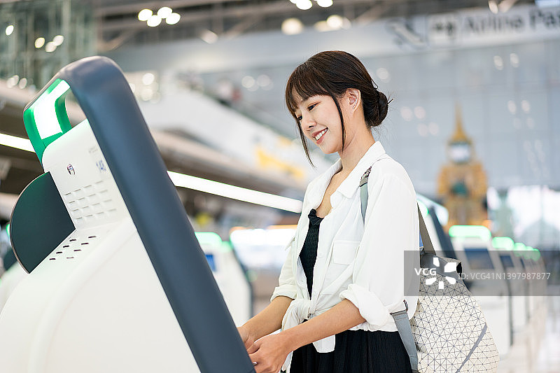 亚洲年轻女人在机场自助值机图片素材