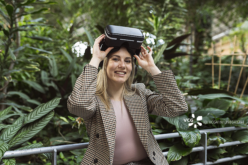 在花园里戴着VR眼镜玩耍的漂亮女人图片素材