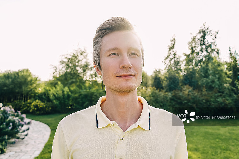 绿意盎然的夏日花园中年轻男子肖像图片素材