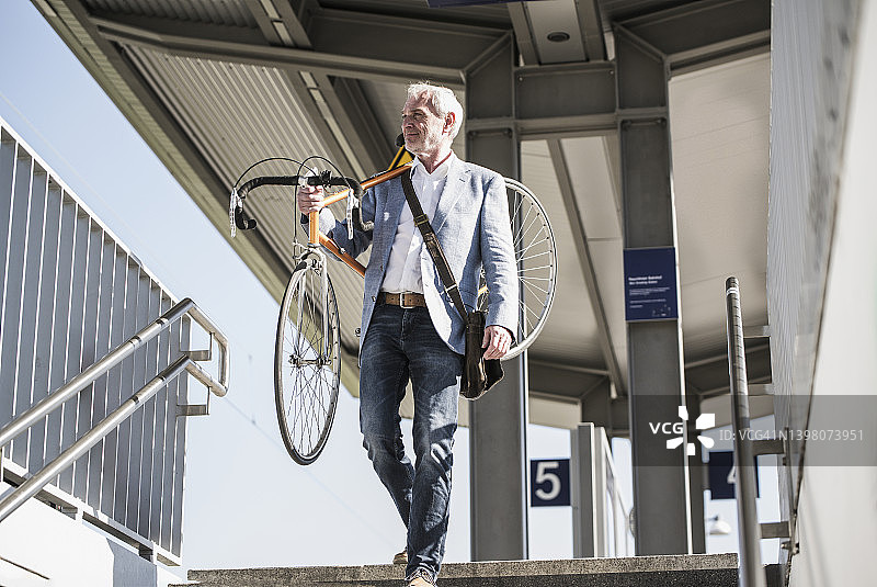 商人肩扛自行车走下楼梯图片素材