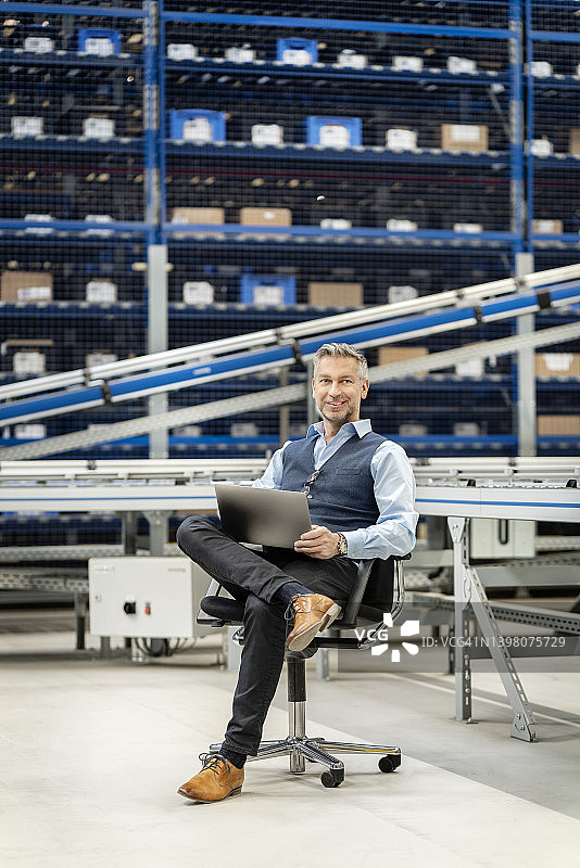 在仓库里翘着二郎腿的中年商人图片素材