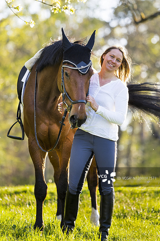 笑容满面的女人和马站在果园里图片素材