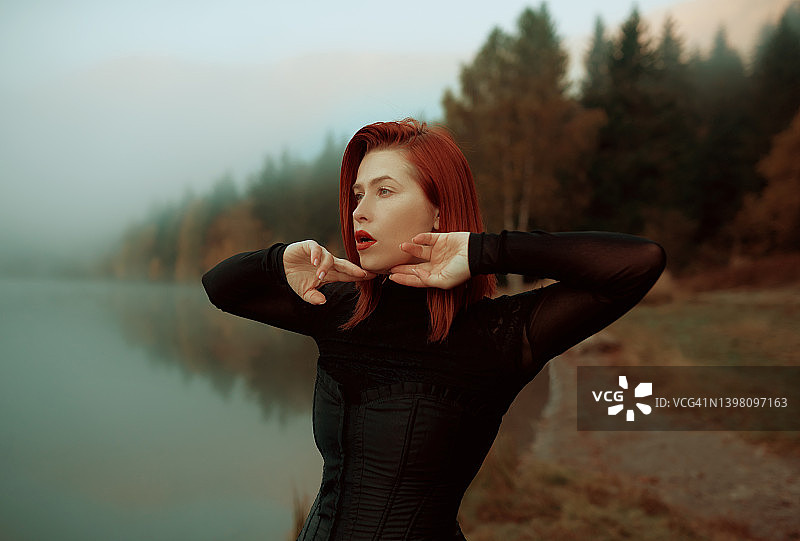 红发女人湖畔半身像看向远方图片素材
