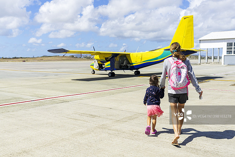 和母亲一起登上前往加勒比海飞机的可爱小女孩图片素材