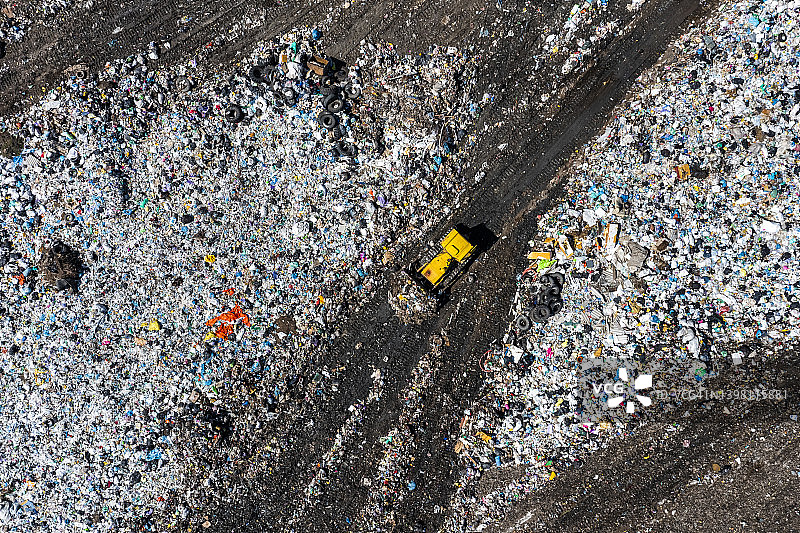 城市垃圾场推土机鸟瞰：污染与过度消费概念图片素材