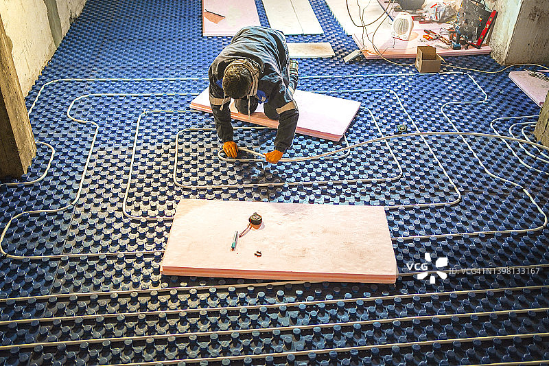 水管工正在完成地板下的暖气管道布置图片素材