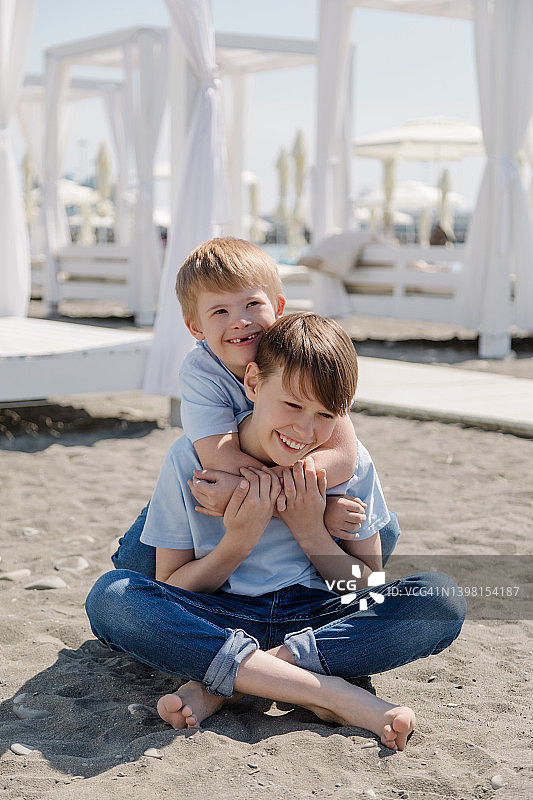 患有唐氏综合症的欧洲小男孩和他的哥哥在沙滩上玩耍图片素材