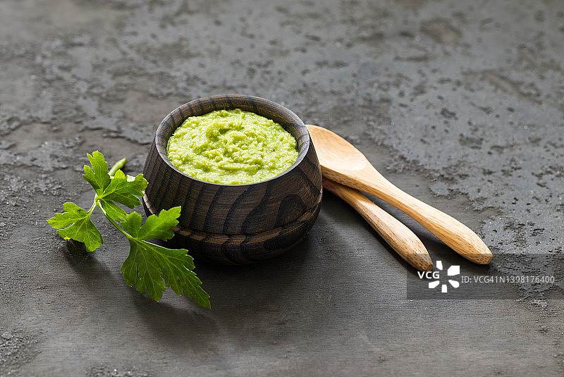 清淡的开胃菜：木制平底锅中的绿色辣根芥末，深灰色背景，乡村风格图片素材