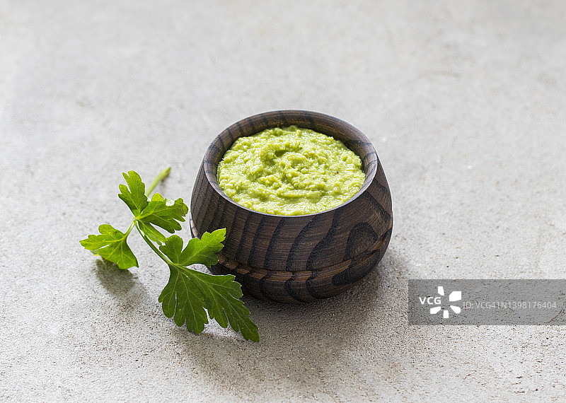 清淡的开胃菜：木制平底锅中的绿色辣根芥末，浅灰色背景，乡村风格图片素材