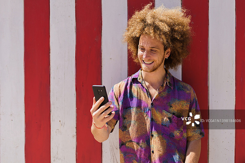 年轻男人微笑地在手机上阅读伴侣的信息图片素材