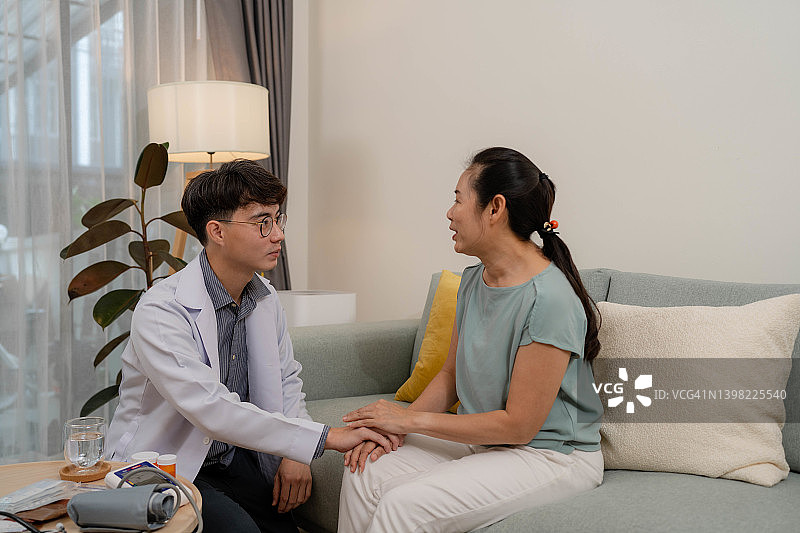 亚洲医生上门拜访老年女患者，咨询老年健康保险图片素材