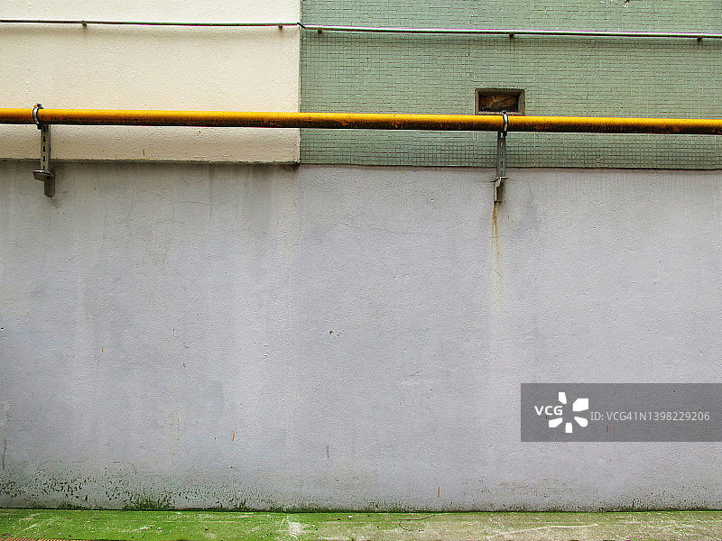 巴黎：空旷的彩绘水泥墙、绿色马赛克、黄色管道和电缆以及脏污的人行道图片素材