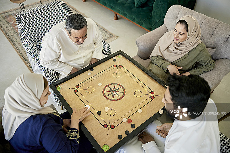 沙特两代同堂家庭在家玩卡罗姆棋图片素材