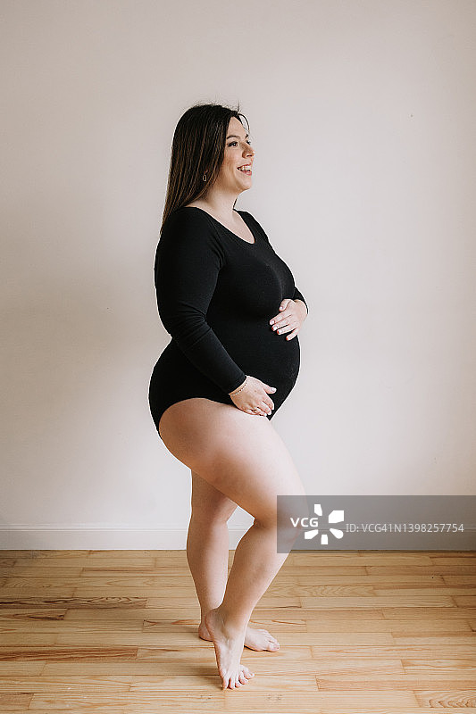 身穿黑色紧身衣抚摸腹部的孕妇肖像图片素材