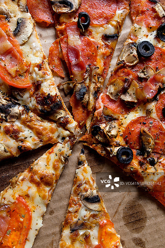 美味的意大利披萨：外卖披萨盒装，白色背景。番茄、意大利辣香肠、培根和奶酪披萨切片，不健康的生活方式快餐理念。图片素材