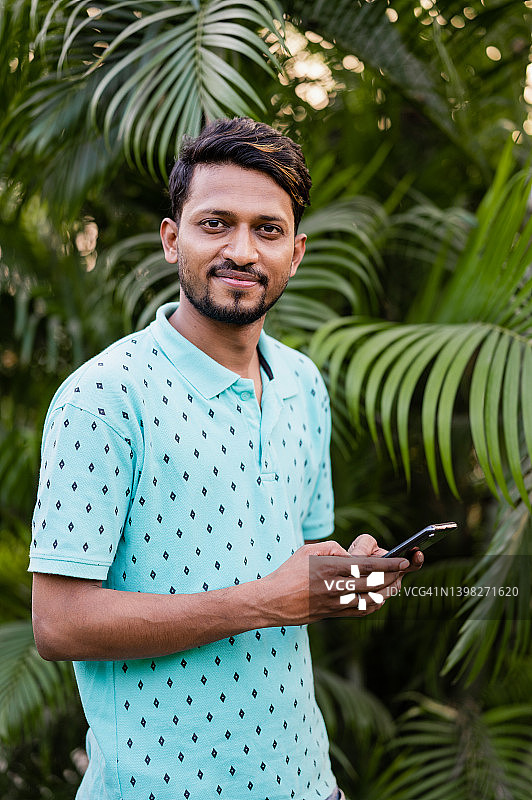 在公园使用智能手机的年轻男人图片素材